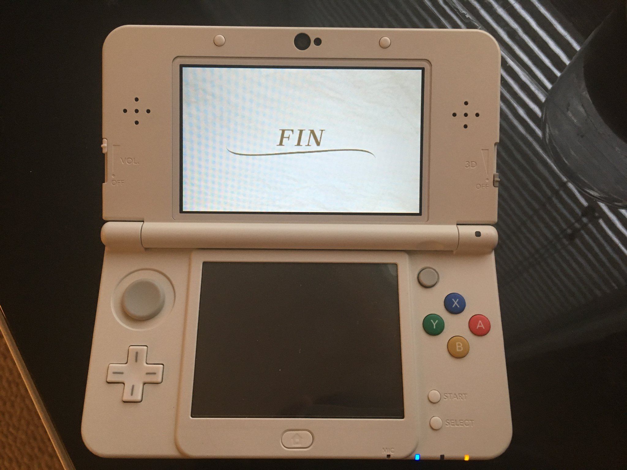 A photo of a 3DS. Bottom screen off, top screen full white with black text: "Fin"